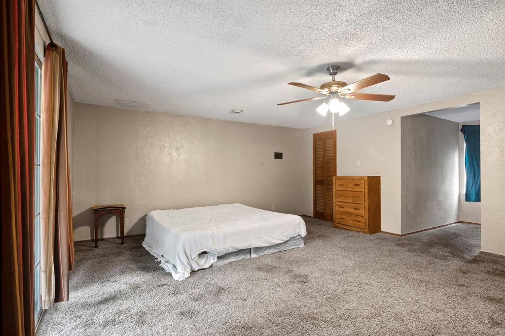 504 East 3rd Street Mount Pleasant, TX 75455 - Photo 18 of 28 a spacious bedroom with a bed and a chandelier