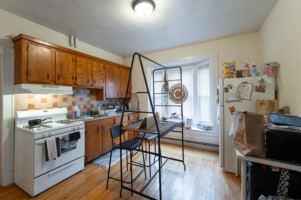 18 Edson Street Lowell, MA 01851 - Photo 24 of 41 a kitchen with stainless steel appliances granite countertop a stove top oven a refrigerator a sink and dishwasher with wooden floor