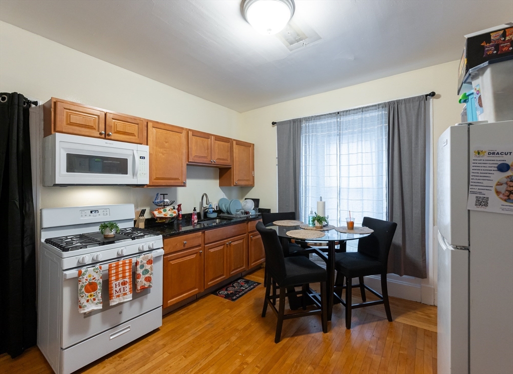 18 Edson Street Lowell, MA 01851 - Photo 32 of 41 a kitchen with stainless steel appliances kitchen island granite countertop a stove a sink a dining table and chairs