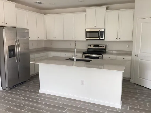 a kitchen with granite countertop a refrigerator stove and microwave