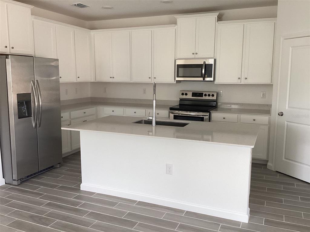 7898 Southwest 74th Loop Ocala, FL 34481 - Photo 5 of 23 a kitchen with granite countertop a refrigerator stove and microwave