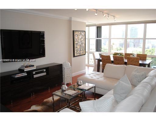 1901 Brickell Avenue, Unit B1711 Miami, FL 33129 - Photo 2 of 9 a living room with furniture a flat screen tv and a floor to ceiling window
