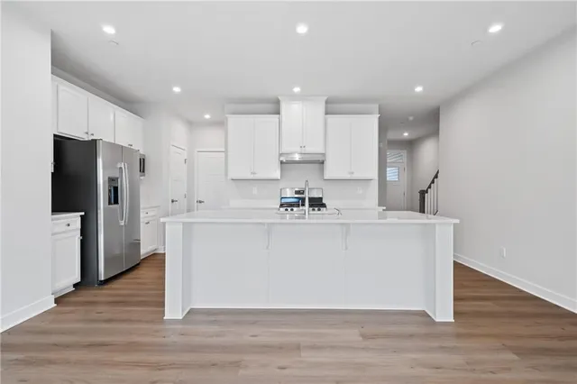 a white kitchen with wooden floor and a refrigerator