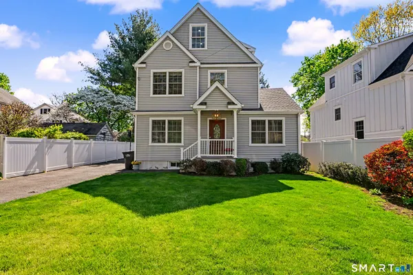 a front view of a house with a yard and trees