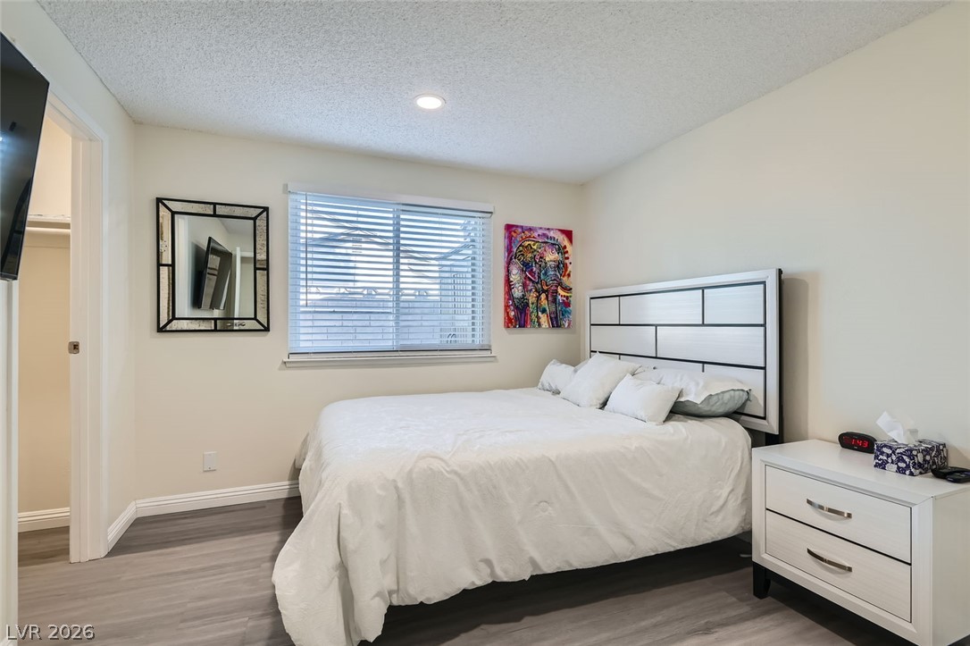 3665 Bronco Road Las Vegas, NV 89103 - Photo 20 of 28 Hardwood-style flooring and a window with blinds create a comfortable and inviting bedroom retreat.