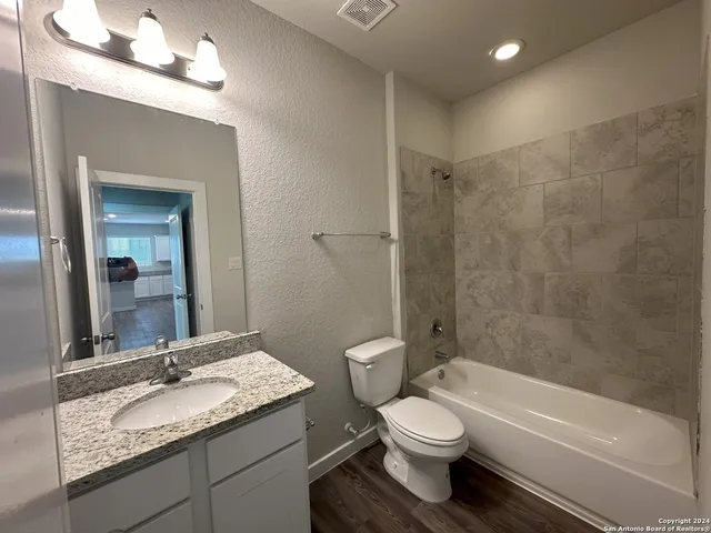 a bathroom with a granite countertop toilet a sink and a mirror