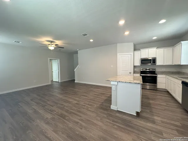 a view of kitchen with granite countertop cabinets and refrigerator