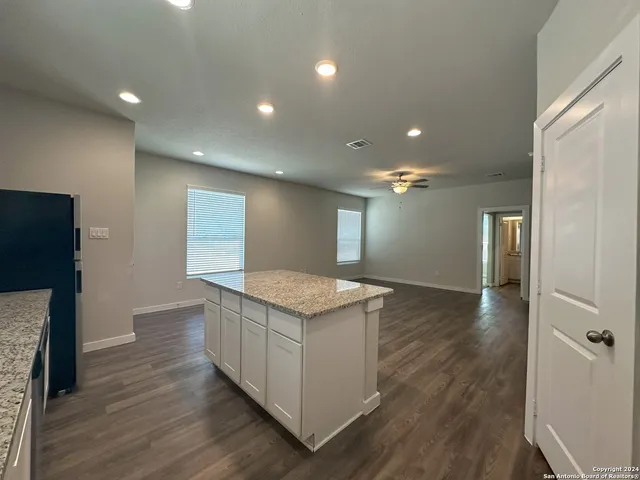 a kitchen with granite countertop a stove and a wooden floor