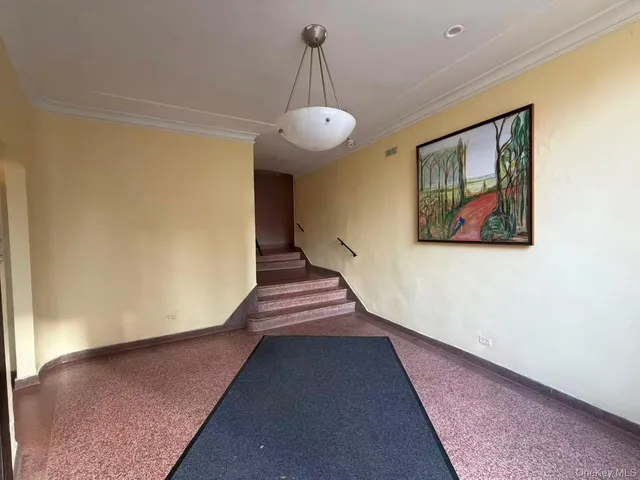 a view of a hallway with wooden floor and a chandelier