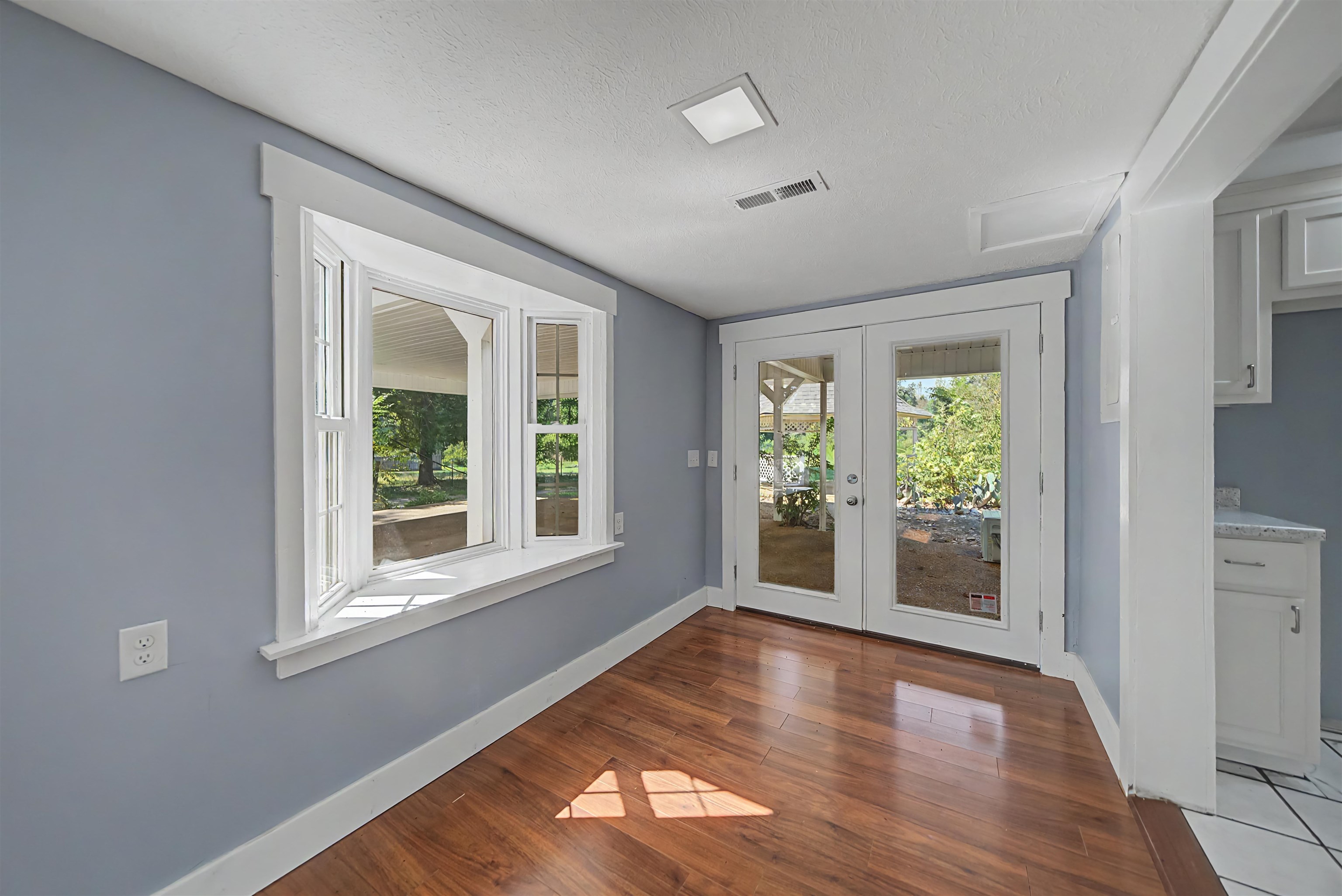 7437 Highway 45 Ramer, TN 38367 - Photo 14 of 36 Wood-finish flooring, bay window, French doors, square ceiling light, and white cabinetry with a light-toned countertop