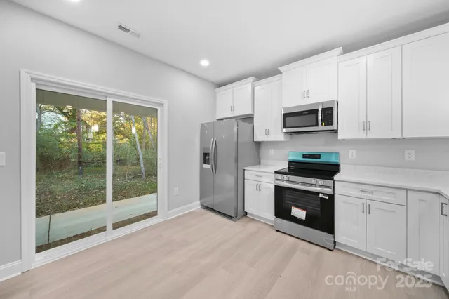 a kitchen with stainless steel appliances granite countertop a refrigerator a stove a microwave a sink and cabinets