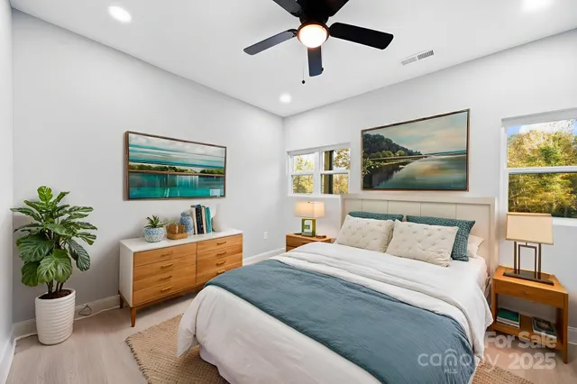 a bedroom with a bed a dresser and potted plant