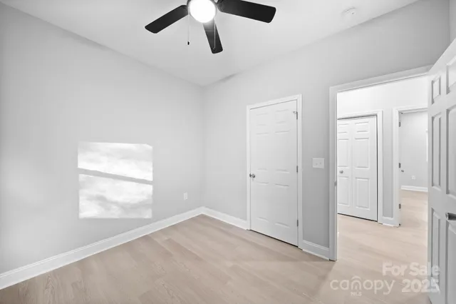 an empty room with windows and ceiling fan