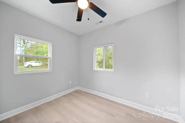 an empty room with a window and ceiling fan