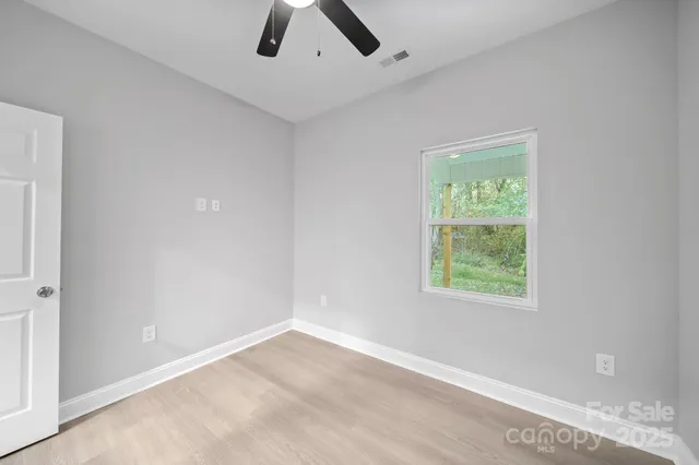 an empty room with a window and a ceiling fan