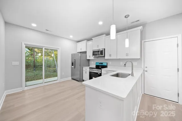 a kitchen with kitchen island a sink a stove a refrigerator and cabinets