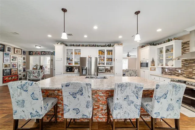 a large kitchen with kitchen island a stove a sink a refrigerator and a dining table with wooden floor
