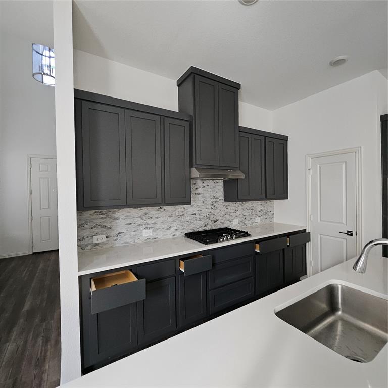2309 Jack Rabbit Way Northlake, TX 76247 - Photo 4 of 28 Modern kitchen featuring dark cabinetry, white countertops, a gas cooktop, and a mosaic tile backsplash