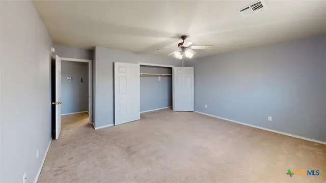 an empty room with a window and a ceiling fan