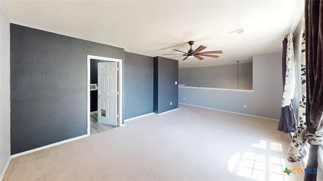 an empty room with a window and ceiling fan