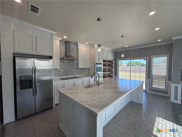 a large kitchen with kitchen island a large counter top stainless steel appliances and cabinets