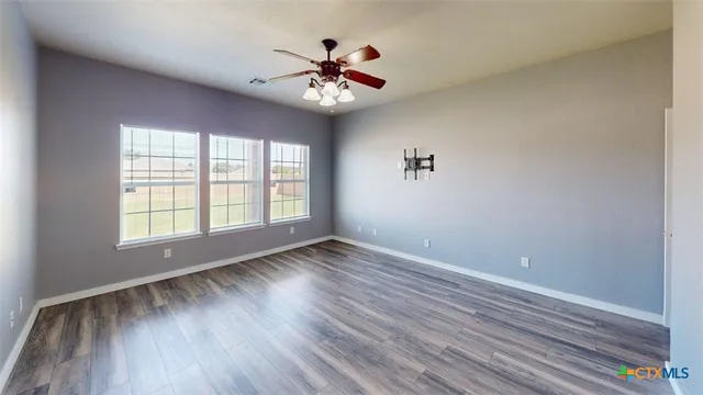 a view of an empty room with wooden floor and a window