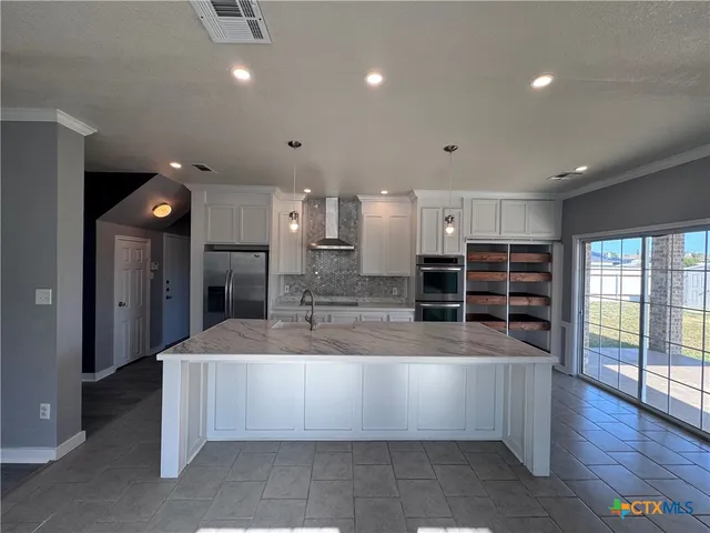 a large kitchen with a large counter top stainless steel appliances and cabinets