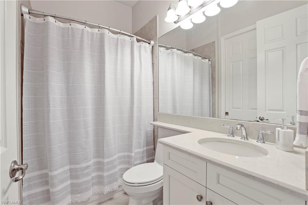 13435 Silktail Drive Naples, FL 34109 - Photo 14 of 27 a bathroom with a sink a toilet and shower curtain
