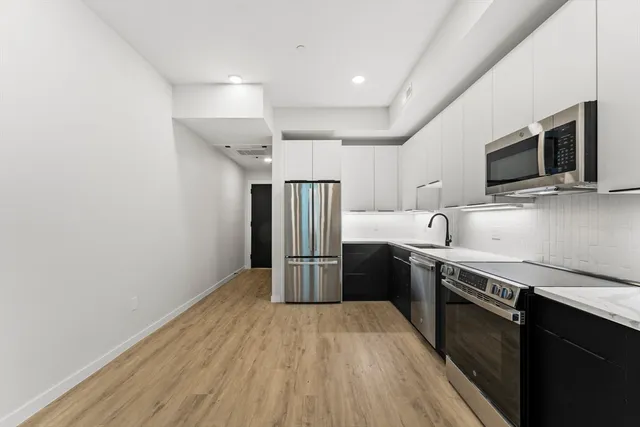 a kitchen with stainless steel appliances granite countertop a refrigerator a sink dishwasher a stove and a microwave oven on granite countertops