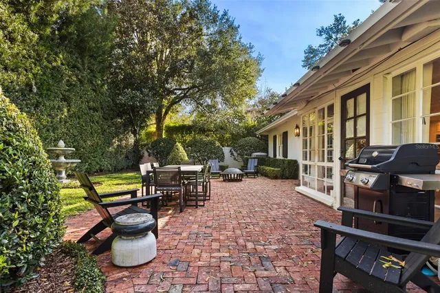 a view of a patio with table and chairs potted plants and a large tree