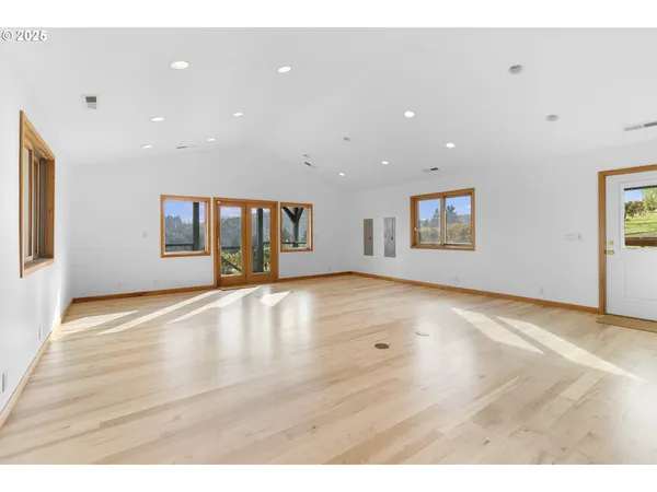 a view of an empty room with window and wooden floor