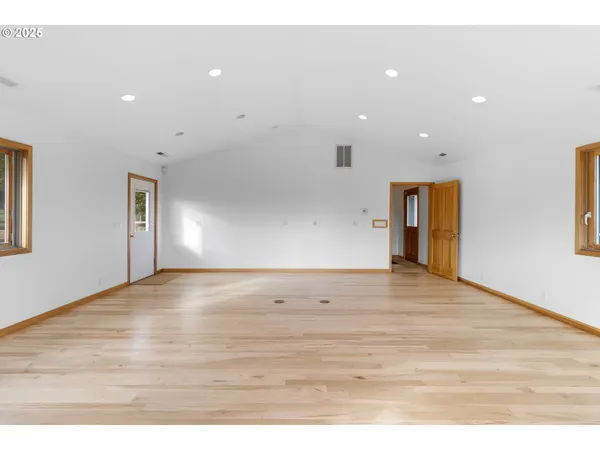 an empty room with wooden floor closet and windows