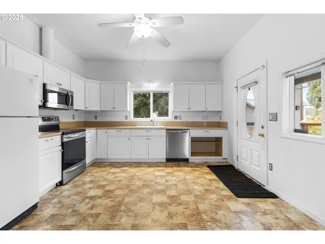 an empty room with wooden floor fireplace and windows