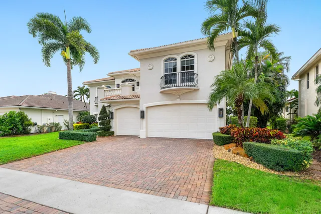 a front view of a house with a garden and trees