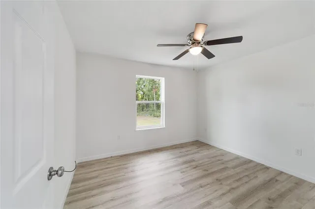 an empty room with wooden floor and ceiling fan