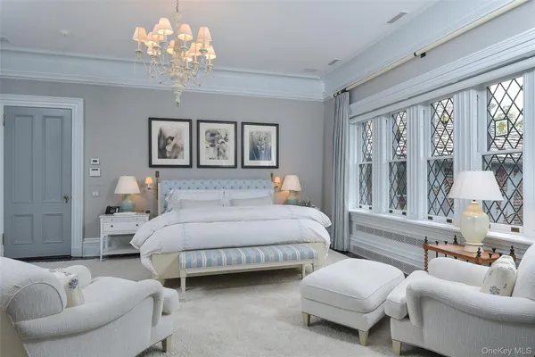 a bedroom with a bed couches and large windows