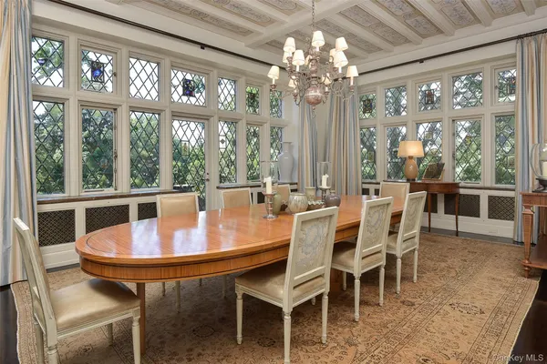 a dining room with furniture a chandelier and large window