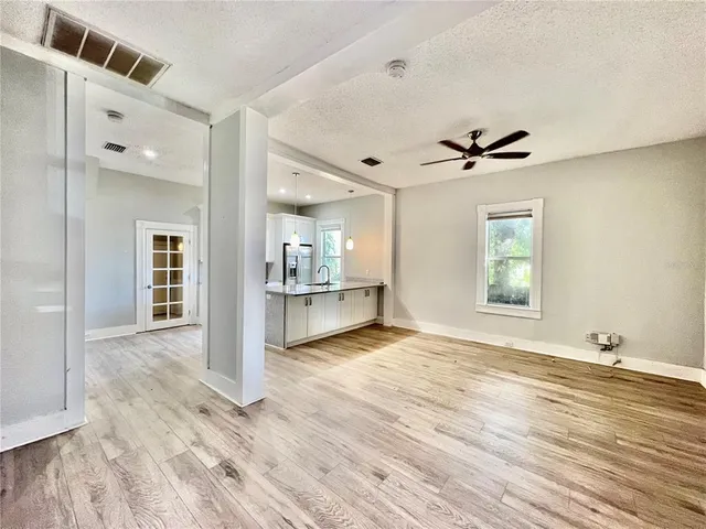 a view of an empty room with window and wooden floor