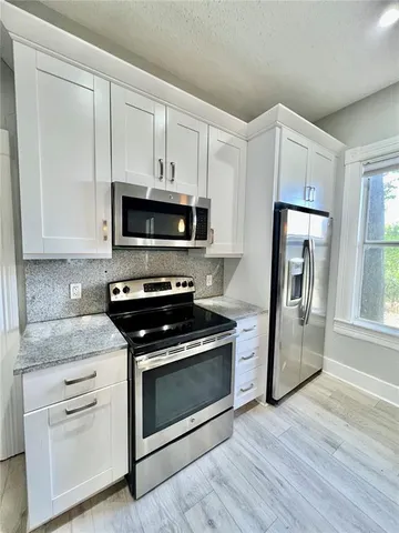 a kitchen with white cabinets stainless steel appliances and wooden floor