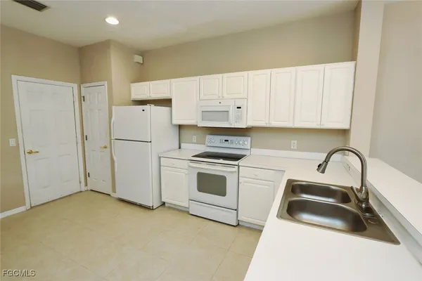 a kitchen with white cabinets and white appliances