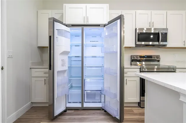 a view of an empty room with wooden floor closet and a window