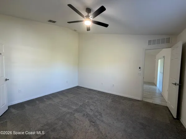 an empty room with closet and a ceiling fan