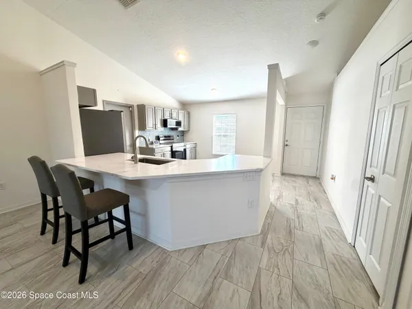 a dining room with kitchen island stainless steel appliances a sink table and chairs