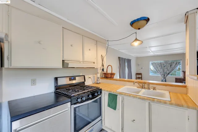 a kitchen with stainless steel appliances a refrigerator a sink dishwasher a stove and white cabinets with wooden floor