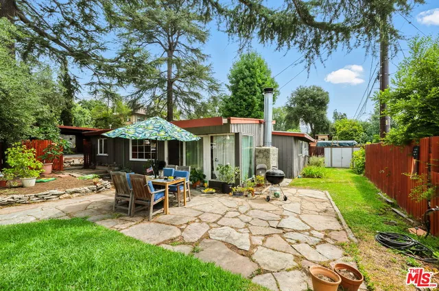 a view of a patio with table and chairs potted plants and large tree