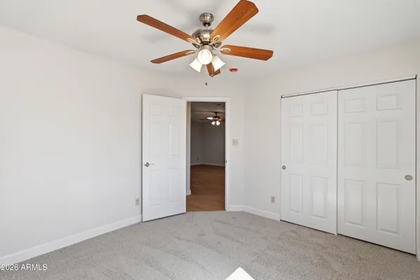 an empty room with closet and a ceiling fan