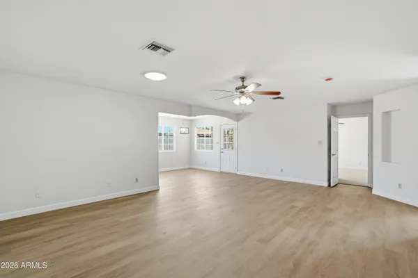 a view of an empty room with chandelier fan and wooden floor