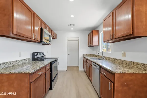 a kitchen with stainless steel appliances granite countertop a sink a stove and a wooden cabinets