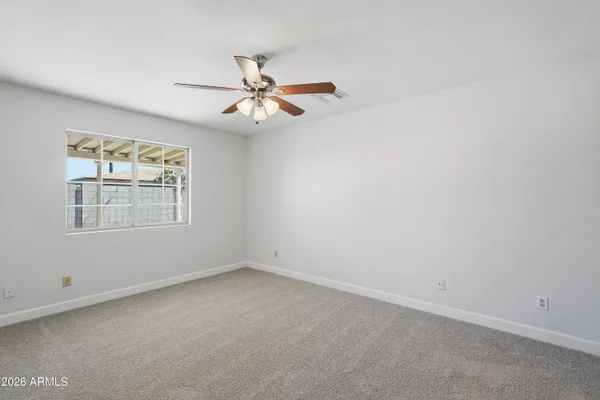 an empty room with windows and fan