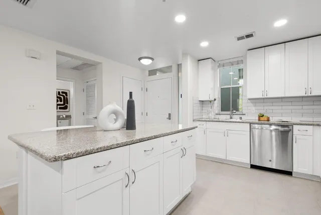 a kitchen with granite countertop white cabinets stainless steel appliances and sink